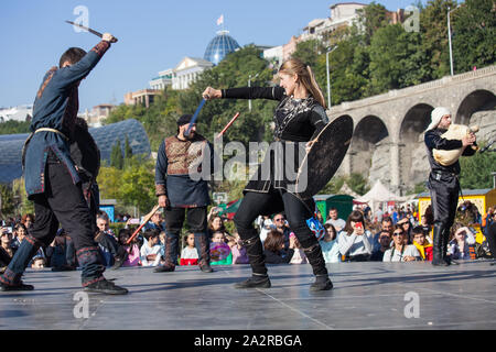 La Georgia, Tbilisi-07 Ottobre 2017: guerrieri vestiti in stile georgiano costumi nazionali tenere coltelli, spade e scudi e lotta su Tbilisoba vacanza. Octob Foto Stock