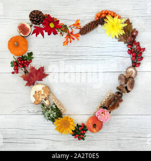 A forma di cuore ghirlanda di autunno con la flora, il cibo e la fauna di legno rustico sfondo. Harvest Festival tema. Vista dall'alto. Foto Stock