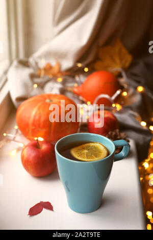 Tazza di tè con il limone contro le zucche, mele e autunno decorazioni sulla finestra. In autunno, home decor concetto. Foto Stock