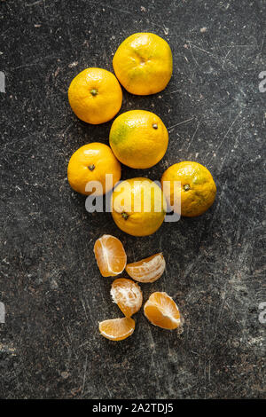 Freschi mandarini giallo sul vecchio tavolo da cucina. Vista dall'alto. Foto Stock