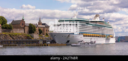 OSLO, Norvegia - Traghetto passa davanti alla Explorer dei mari a Royal Caribbean Cruise nave ormeggiata presso la Fortezza di Akershus Oslo waterfront. Foto Stock