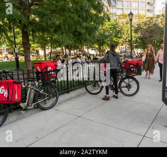 Una consegna GrubHub lavoratore parcheggia la sua moto e si unisce agli altri lavoratori di attendere che un lavoro in un parco di Greenwich Village di New York venerdì, 27 settembre 2019. (© Richard B. Levine) Foto Stock