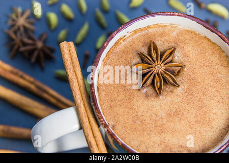 Calda tazza di tè Chai con ingredienti (anice stellato, cannella, cardamomo verde) sul tavolo Foto Stock