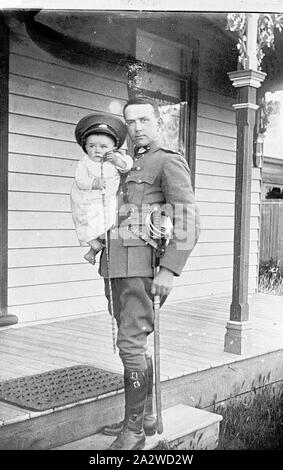 Negativo - Officer & bambino su una veranda, Horsham, Victoria, 1914, fotografia di Otto Emil Müller (Muller/Miller) e suo figlio Ralph. La fotografia è stata scattata nel 1914 mentre Otto era che serve come il cittadino forza militare ufficiale di Area a Horsham. Otto Emil Müller è nato nel 1881 a Horsham a tedesco nato genitori Sophie Landmann e Heinrich Wilhelm (o Henry William) Müller. Durante la guerra boera ha arruolato con il quinto contingente Vittoriano di un privato Foto Stock