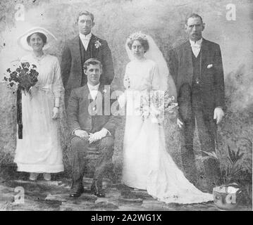 Negativo di vetro - Gruppo Studio ritratto della festa di nozze, circa 1910s, una in bianco e nero, metà piastra negativa di copia con un ritratto in studio di una festa di nozze, circa 1910s. Il govern è seduto mentre la moglie, con bouquet ampio e lungo velo nuziale, damigella con bouquet e due groomsmen stand intorno a lui Foto Stock