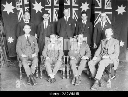 Vetro negativo - Maschio Ritratto di gruppo con bandiere, circa 1930, una in bianco e nero, metà piastra negativa con un ritratto di gruppo di uomini in abiti contro uno sfondo di ciò che sembrano essere Australian flag. Gli uomini sono posizionati in due righe, con due uomini in centro seduto in alte sedie e un altro due seduti in sedie regolari.La provenienza di questa immagine non è chiara, ma è venuto da Kodak museo aziendale a Coburg Foto Stock