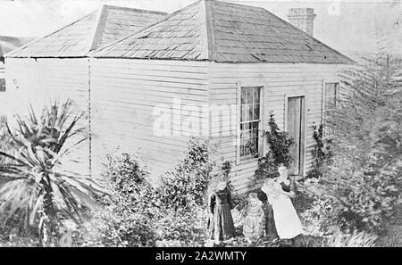 Negativo - donna e bambini al di fuori di una casa Weatherboard, Ballarat, Victoria, circa 1890, una donna con due bambini e un bambino nel giardino di fronte a una piccola casa in legno Foto Stock