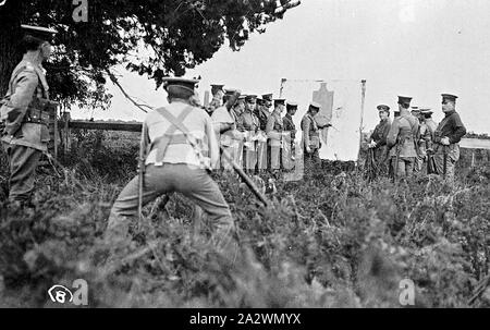 Negativo - di soldati a Gunnery pratica, Horsham District, Victoria, post 1910, soldati a gunnery pratica. Il soldato in primo piano è accovacciato dietro un treppiede, un ufficiale in background è rivolta verso le hit su un bersaglio di grandi dimensioni con la sagoma di un uomo di figura su di esso. Il tipo di arma utilizzata è oscurato da del soldato Foto Stock