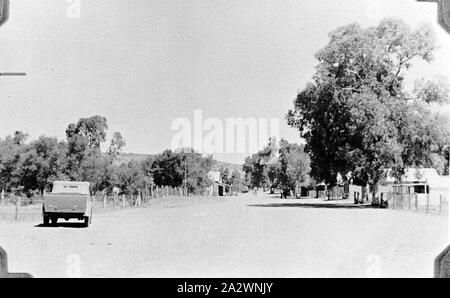 Negativo - Alice Springs, Northern Territory, 1937, un motore di guida auto giù una ampia strada alberata in Alice Springs Foto Stock