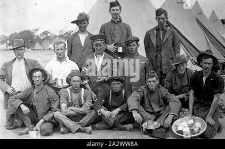 Negativo - soldati rilassarsi di fronte di tende, Esercito Broadmeadows Camp, Victoria, la guerra mondiale I, 1915, un gruppo di soldati di fronte alle loro tende. Alcuni sono holding tazze e vi è una vasca contenente un certo numero di tazze sulla destra Foto Stock