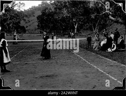 Negativo - Ensay District, Victoria, circa 1905, tre donne e una bambina gioca raddoppia sul campo da tennis a "Bindi' stazione. Un gruppo di famiglia guardare dal margine Foto Stock