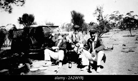 Negativo - Swan Hill District, Victoria, circa 1930, tre uomini in abiti di cricket insediato da un mg auto. Essi vengono a bere birra e hanno un pranzo a picnic accanto a loro. Foto Stock