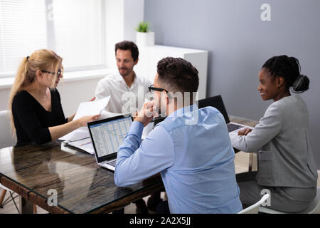 Un gruppo di giovani imprenditori discutendo insieme durante una riunione in ufficio Foto Stock