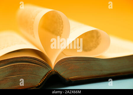 Oro, giallo incandescente pagine di una bibbia formando un cuore Foto Stock