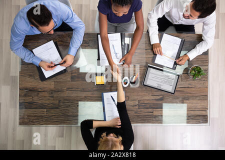 Le persone che ricercano Manager maschio femmina Congratulazioni candidato durante il colloquio in ufficio Foto Stock