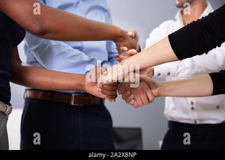 Gruppo di multi razziale imprenditori stringono le mani con ogni altro in ufficio Foto Stock