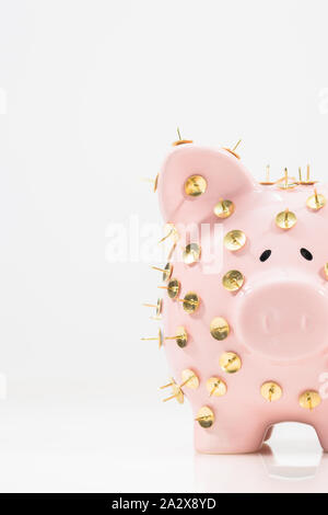 Immagine concettuale che illustra la protezione dei risparmi e degli investimenti che mostra una banca rosa piggy protetta da tacchi di disegno e isolata contro il bianco. Foto Stock