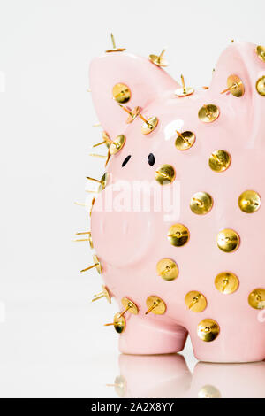 Immagine concettuale che illustra la protezione dei risparmi e degli investimenti che mostra una banca rosa piggy protetta da tacchi di disegno e isolata contro il bianco. Foto Stock