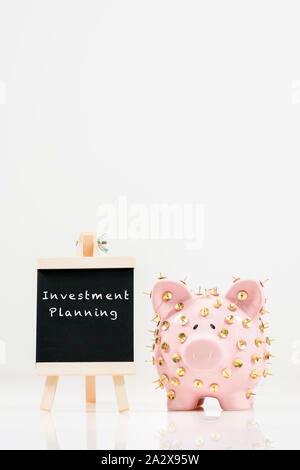 Immagine concettuale che illustra la protezione dei risparmi e degli investimenti che mostra una banca rosa piggy protetta da tacchi di disegno e isolata contro il bianco. Foto Stock