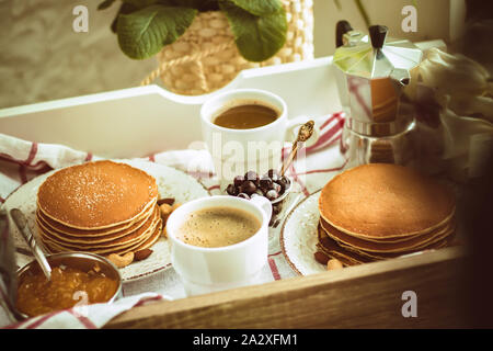 Appena in casa tradizionale colazione per due: pancake, tazze da caffè sul vassoio con panno checkred Foto Stock