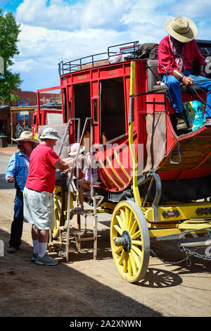 Un rosso stagecoach scarica i passeggeri con l aiuto di un cowboy nell'area turistica e commerciale di lapide storica, AZ, Stati Uniti d'America Foto Stock