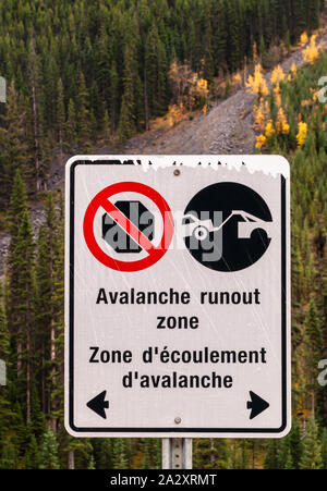 Una valanga di scentratura segno zona scritti in inglese e in francese sul lato della strada nelle montagne rocciose canadesi Foto Stock
