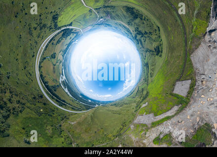 360 grado immagine panoramica di un mondo astratto rovesciato con il verde dei prati intorno a un ovale sky con le nuvole Foto Stock