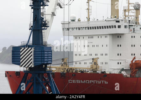 Sevmorput - nucleare russo-powered accendino rompighiaccio a bordo di una nave portante, contenitore nave ancorata in container terminal Seaport. Oceano Pacifico Foto Stock