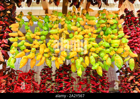 Molti giallo e peperoncino rosso appendere a corde sul mercato in Portogallo Foto Stock