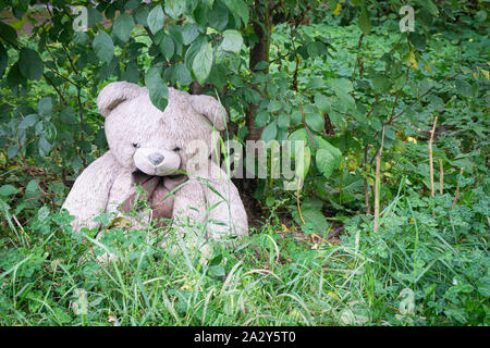 Abbandonato il giocattolo morbido recare in cantiere sotto la struttura. Simbolo della triste e abbandonare. lonely concetto internazionale di bambini scomparsi. Fine dell'infanzia Foto Stock