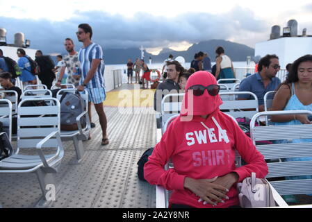 Settembre 29, 2019, Moorea, Polinesia Francese: una donna protegge se stessa dal vento con una cappa su un traghetto nei pressi di Porta Vaiare..Moorea è un alto isola in Polinesia francese formata come un vulcano di circa 1,5 a 2,5 milioni di anni fa. Ha circa 17.000 abitanti ed è visitato da migliaia di turisti ogni anno. L'ananas è il principale prodotto agricolo dell'isola. (Credito Immagine: © Giovanni Milner/SOPA immagini via ZUMA filo) Foto Stock