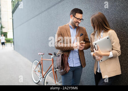 La gente di affari di discutere e sorridere mentre camminando insieme all'aperto Foto Stock