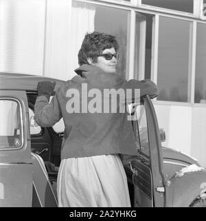 La guida negli anni sessanta. Una donna alla sua auto una Volkswagen maggiolino. Indossava un mantello, un breve giacca di pelle, occhiali e guanti di protezione. La Svezia 1962 Foto Stock