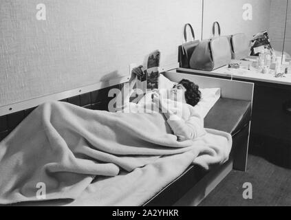 Una giovane donna nella sua camera di albergo giace nel suo letto di lettura. Anni Cinquanta Foto Stock