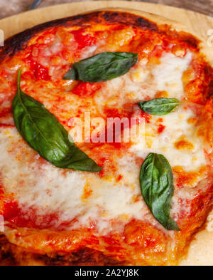 Freschi Fatti in casa Italian Pizza Margherita con basilico su sfondo rustico. Foto Stock