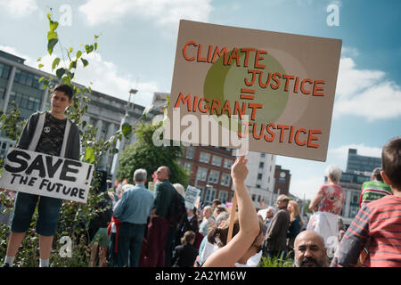 Il dimostratore con giustizia climatica migrante targhetta giustizia, xx settembre del clima globale sciopero, Piazza del Mercato Vecchio, Nottingham East Midlands, Inghilterra Foto Stock