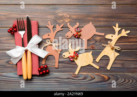 Vista superiore della vacanza di oggetti su sfondo di legno. Utensili legato con nastro sul tovagliolo. Close up di decorazioni natalizie e di renna. Anno nuovo din Foto Stock