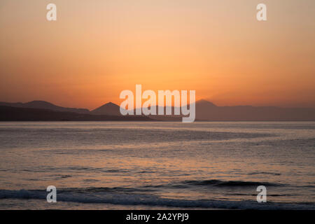 Tramonto sul Teide Tenerife come visto dalla spiaggia di Las Canteras a Las Palmas de Gran Canaria, Teide getta un' ombra sulla haze Foto Stock