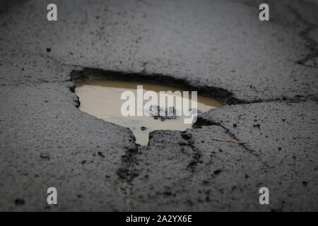 I profondi pozzi in una vecchia strada nella necessità di manutenzione Foto Stock