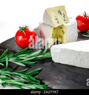 Assortimento di formaggi sulla tavola di legno. Camembert, Formaggi a Muffa Blu, mozzarella con pomodori Foto Stock