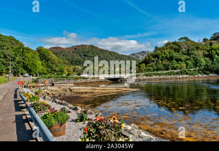 GAIRLOCH HARBOUR WESTER ROSS SCOZIA GUARDANDO VERSO LA STRADA PRINCIPALE E IL PONTE CON FIORI E VASCHE IN ESTATE lungo la strada del porto Foto Stock