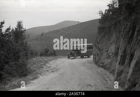 Anni '1930, storica Jugoslavia pre-bellica, in campagna un autobus locale su una strada di montagna polverosa e sabbiosa. Lo stato multinazionale nacque nel 1918 e la formazione del Regno di serbi, croati e sloveni, comunemente noto come Jugoslavia, dominato da tre catene montuose principali, tra cui le Alpi dinariche della penisola balcanica. Foto Stock