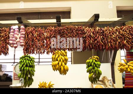 Il peperoncino, le banane e le cipolle che pendevano dal soffitto nel negozio di generi alimentari (Madeira, Portogallo) Foto Stock