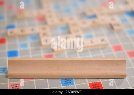 0 vuoto in legno piastrelle scrabble su una piastrella-rack, per voi per riempire la propria parola. Sullo sfondo di una scheda vintage, fuori fuoco con spazio di copia Foto Stock