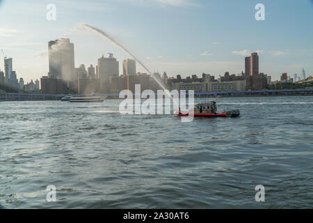 La città di New York, circa 2019: FDNY fire barca la spruzzatura di acqua dal tubo flessibile usato per combattere ed estinguere incendi in mare di proteggere il porto di New York e sulle vie navigabili interne Foto Stock