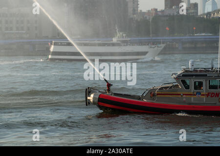 La città di New York, circa 2019: FDNY fire barca la spruzzatura di acqua dal tubo flessibile usato per combattere ed estinguere incendi in mare di proteggere il porto di New York e sulle vie navigabili interne Foto Stock