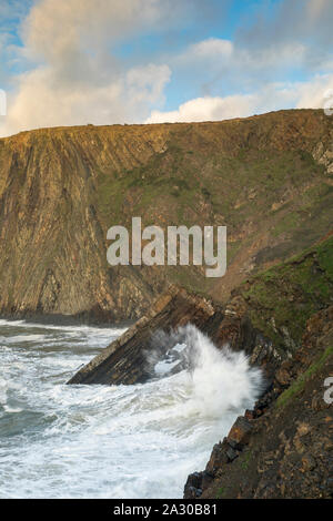 Onde infrangersi su una pietra naturale arch sotto le scogliere di hartland, North Devon, Regno Unito Foto Stock