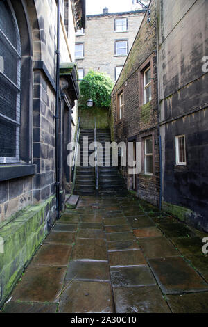 Uno stretto vicolo tra due edifici in pietra che conduce a due voli di gradini ripidi nella città di Leeds, West Yorkshire Foto Stock