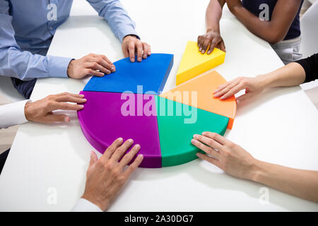 Elevato angolo di visione del business le mani il collegamento Multi pezzi colorati del grafico a torta Foto Stock