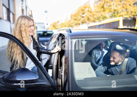 Felice bionda le donne sedute all'interno della vettura con i suoi amici Foto Stock